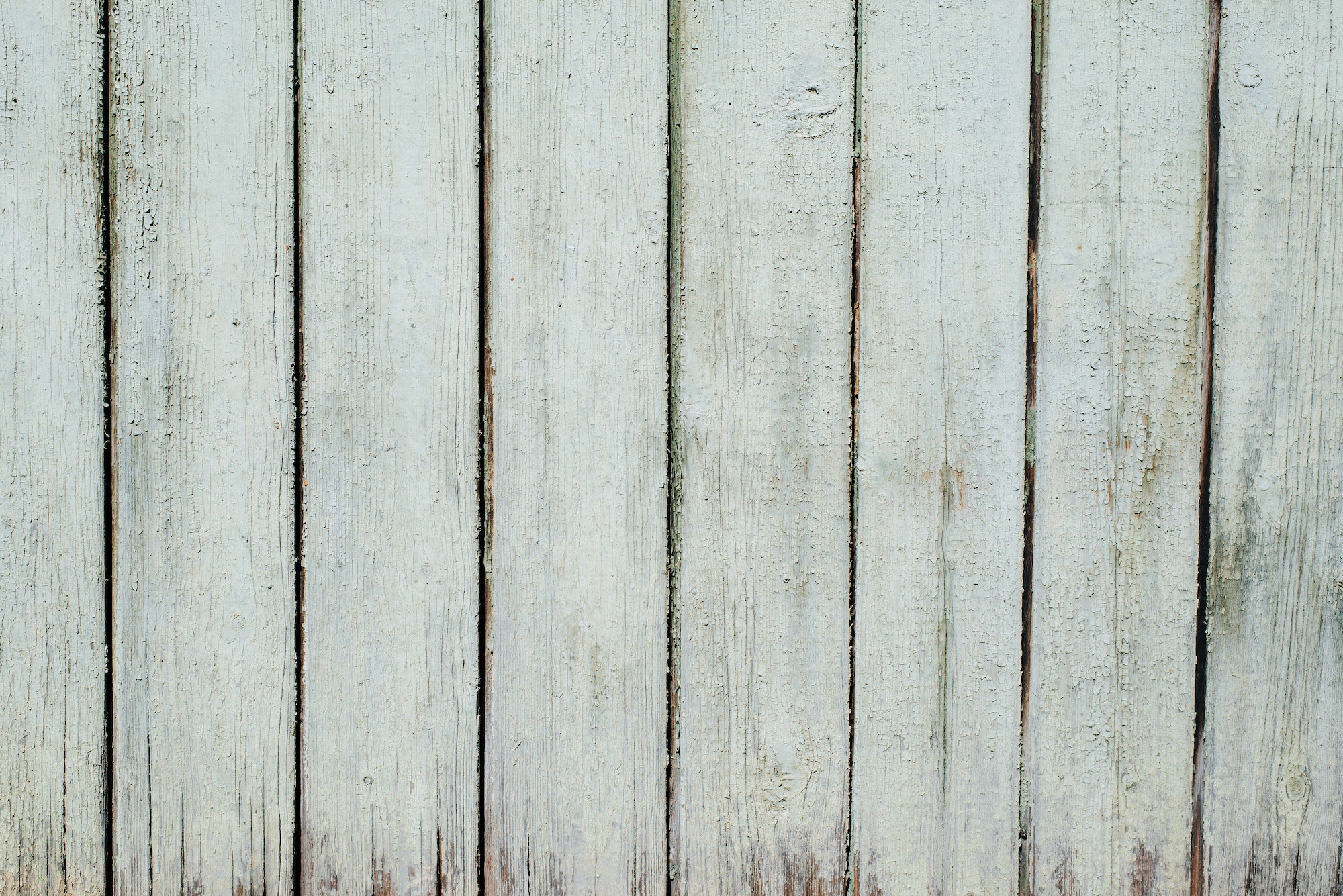 Wooden fence with green old paint, vertical boards, texture background exterior