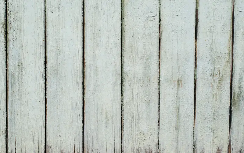 Wooden fence with green old paint, vertical boards, texture background exterior