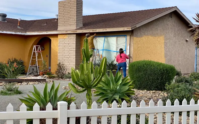 A couple doing home maintenance painting the exterior of their house together