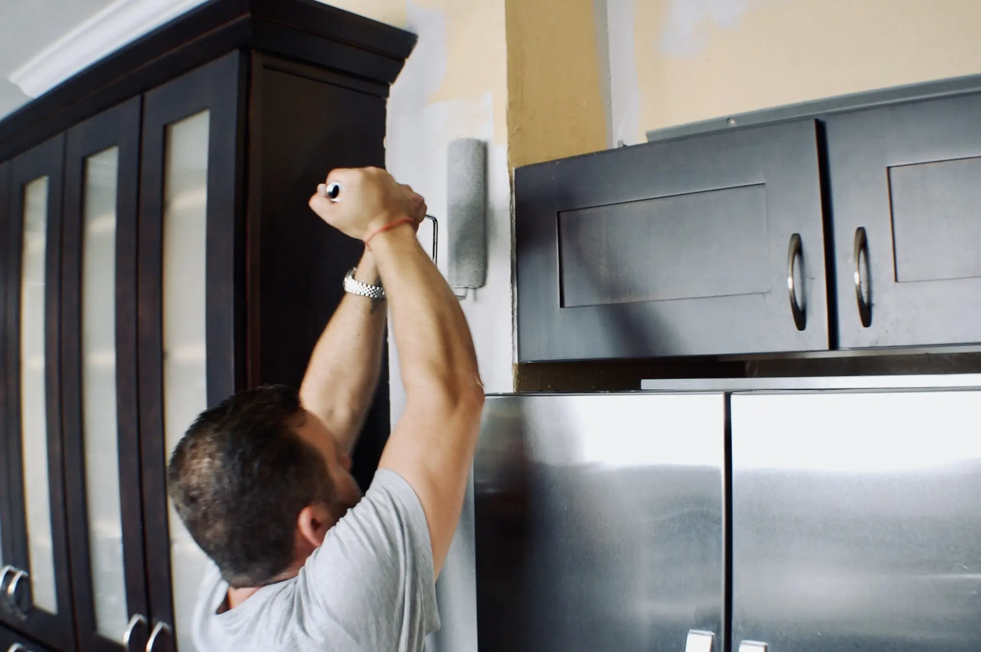 Man doing interior painting in South King County, freshening up walls around kitchen cabinets and appliances.