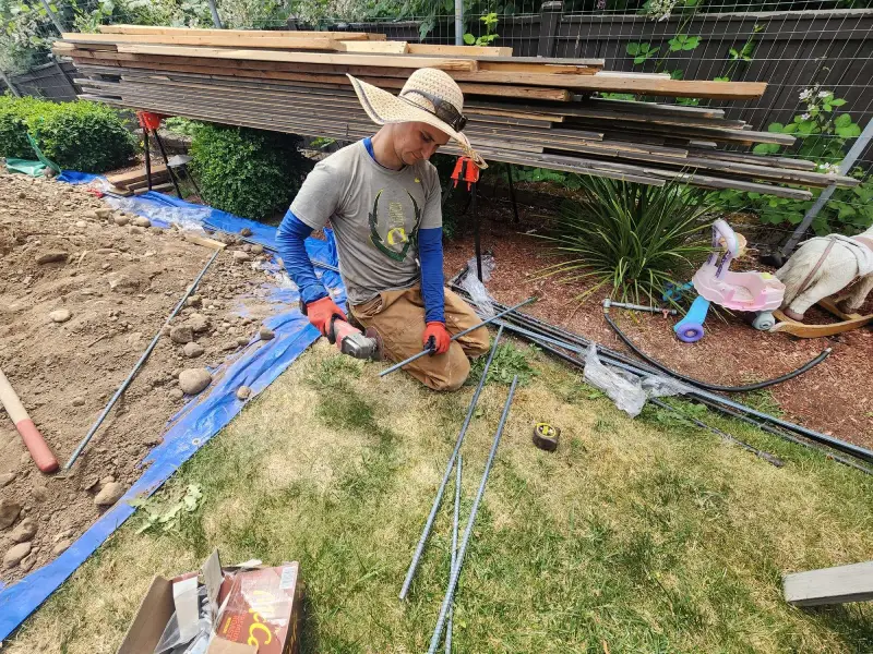 Worker measuring and cutting rods for outdoor work, showing active home renovation contractors near me for quality service.