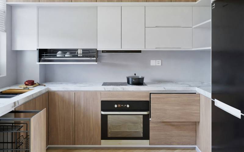 Modern kitchen with wood laminate lower cabinets and white upper cabinets, featuring a marble countertop and built-in appliances.
