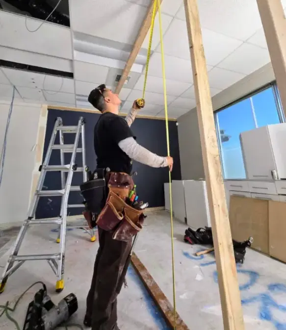 Skilled home remodeler in South King County measuring wood beams during an indoor renovation project.