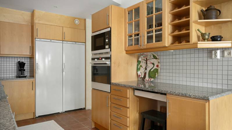 Traditional kitchen with light wood cabinets, granite countertops, and built-in appliances in a warm, functional cooking space.