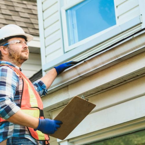 A roofing contractor inspects a residential roof and gutters, ensuring quality workmanship and reliable home protection.
